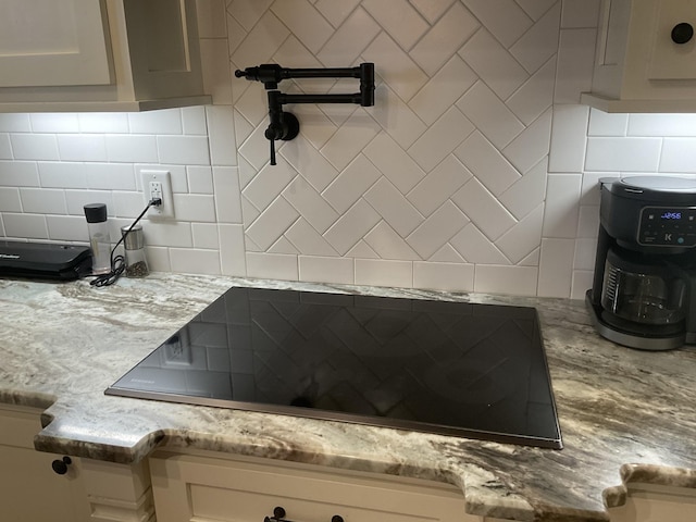 200 Marlin Rd, White House, TN 37188 - interior details featuring light stone counters, backsplash, white cabinets, and black electric cooktop
