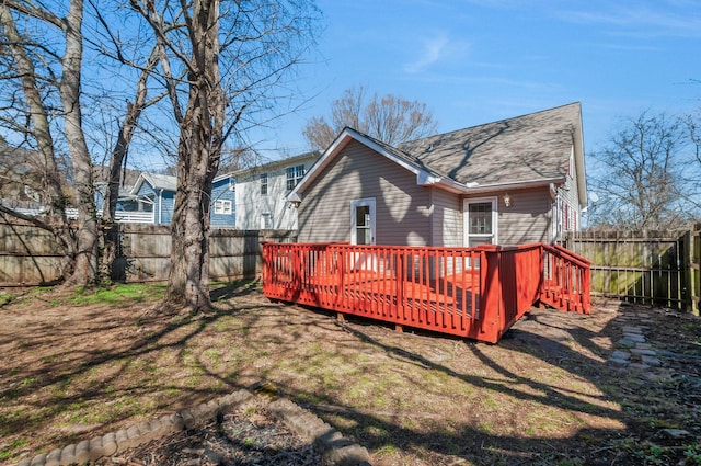 rear view of house featuring a yard, a wooden deck, roof with shingles, and a fenced backyard