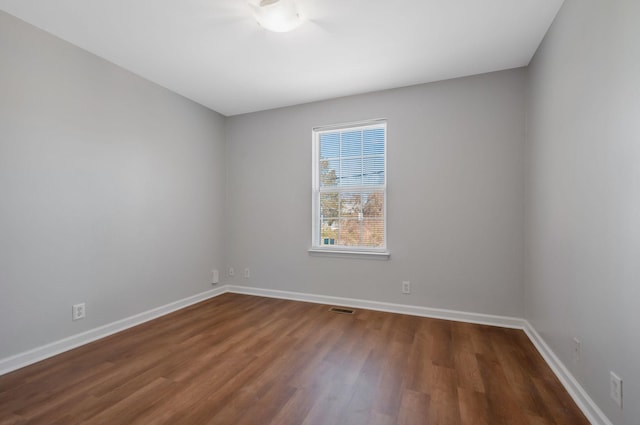 unfurnished room with visible vents, baseboards, and dark wood-style flooring