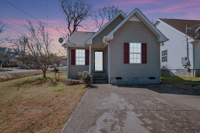 view of front of property with a shingled roof, a lawn, entry steps, and crawl space