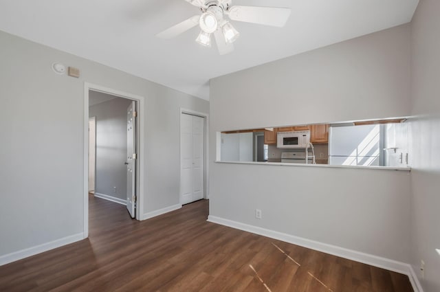 empty room with baseboards, a ceiling fan, and dark wood-style flooring