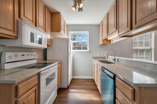 kitchen featuring dark wood-style floors, white appliances, baseboards, and a sink