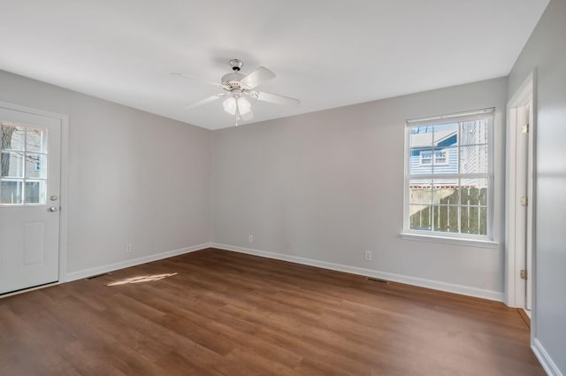 unfurnished room with ceiling fan, visible vents, baseboards, and wood finished floors