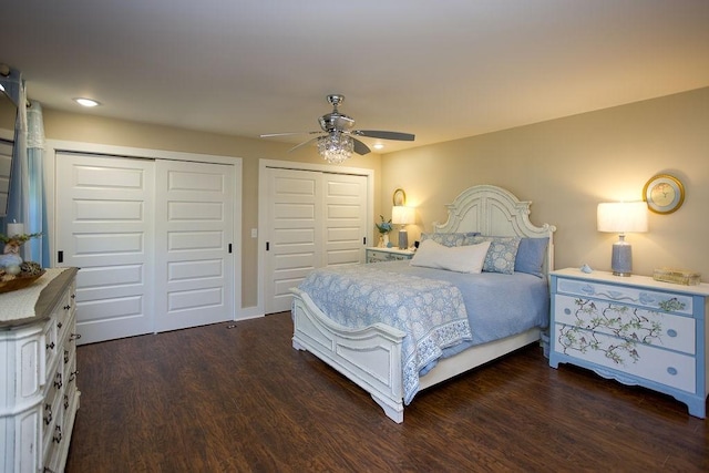 bedroom with a ceiling fan, two closets, and dark wood-style flooring