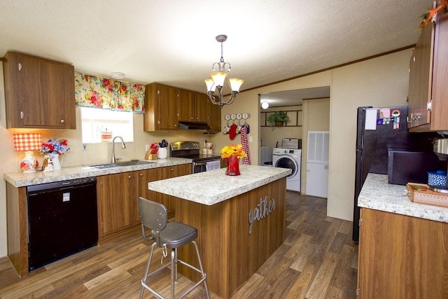 kitchen with brown cabinets, black appliances, a sink, washer / clothes dryer, and dark wood finished floors