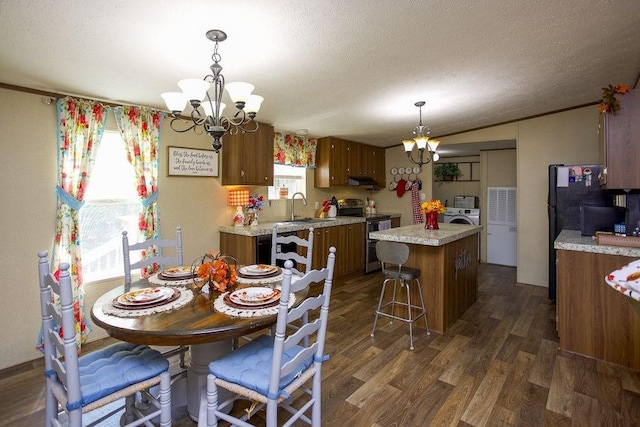 dining space featuring an inviting chandelier, washer / dryer, dark wood-style flooring, and a textured ceiling