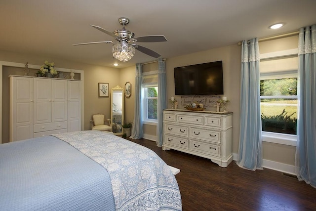 bedroom with a closet, baseboards, dark wood finished floors, and a ceiling fan