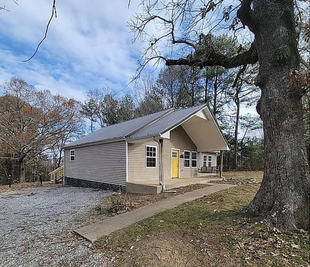 view of side of property with metal roof and gravel driveway