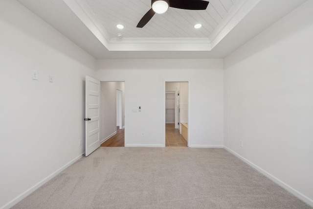 unfurnished bedroom with a tray ceiling, recessed lighting, carpet, and baseboards