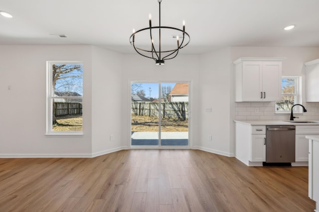 unfurnished dining area with light wood-style flooring, a wealth of natural light, and a sink
