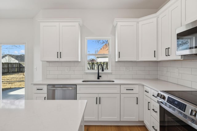 kitchen featuring white cabinets, stainless steel appliances, light countertops, and a sink