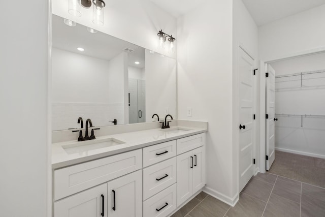 bathroom with a sink, a walk in closet, double vanity, and a shower stall