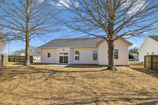 rear view of property featuring a patio area, a yard, and fence