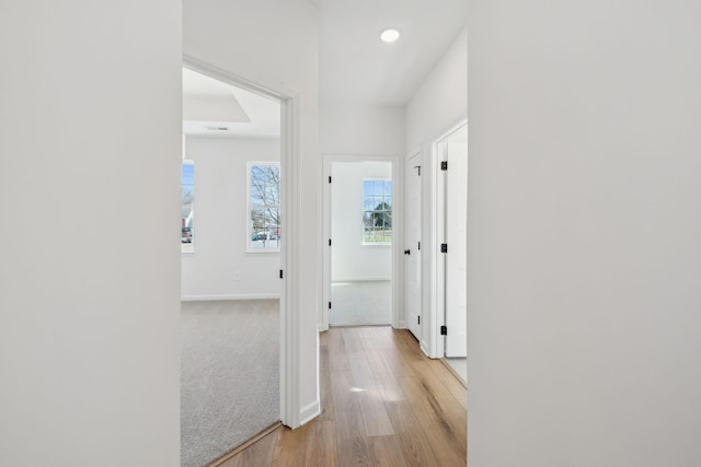 hall featuring light wood finished floors, recessed lighting, and baseboards