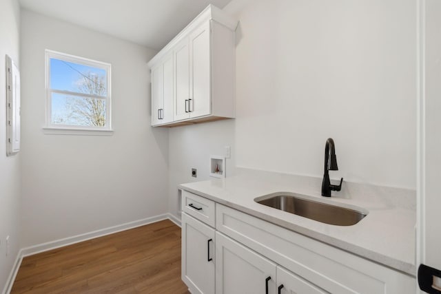washroom with wood finished floors, hookup for an electric dryer, cabinet space, a sink, and washer hookup
