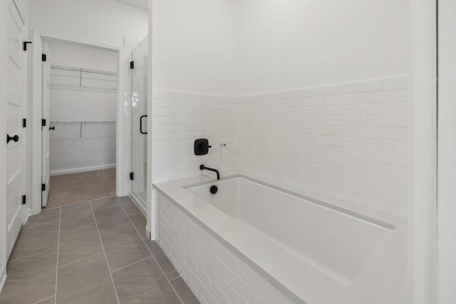 full bath featuring a shower stall, a spacious closet, a bath, and tile patterned floors