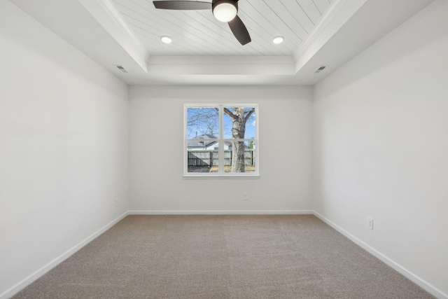 empty room with visible vents, baseboards, a tray ceiling, carpet flooring, and a ceiling fan