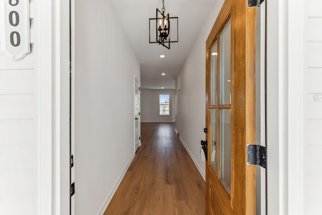 hall with a notable chandelier, recessed lighting, baseboards, and wood finished floors