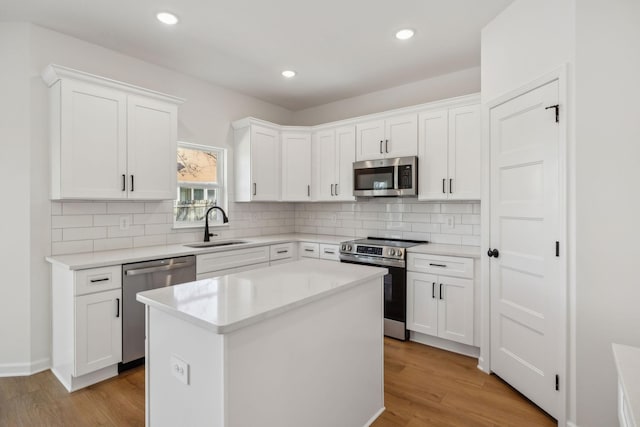 kitchen with backsplash, light wood finished floors, appliances with stainless steel finishes, and a sink