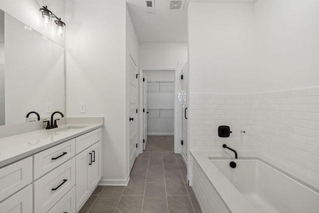 bathroom featuring a spacious closet, visible vents, a garden tub, tile patterned floors, and vanity