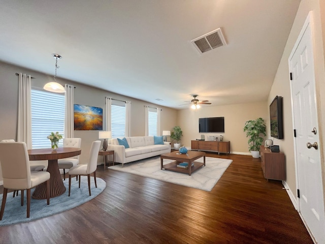 living area with ceiling fan, visible vents, baseboards, and wood finished floors