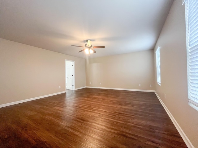 unfurnished room with a ceiling fan, dark wood-style floors, and baseboards