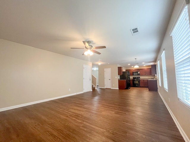 unfurnished living room featuring a ceiling fan, visible vents, dark wood-style flooring, and baseboards