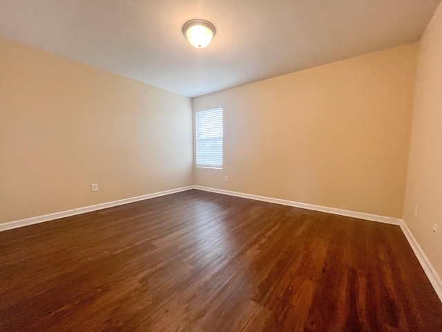 empty room featuring baseboards and dark wood-style floors