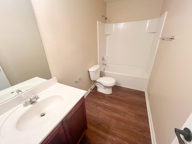 bathroom featuring toilet, wood finished floors, baseboards, bathing tub / shower combination, and vanity