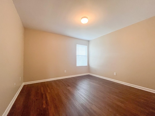 empty room with baseboards and dark wood-style flooring