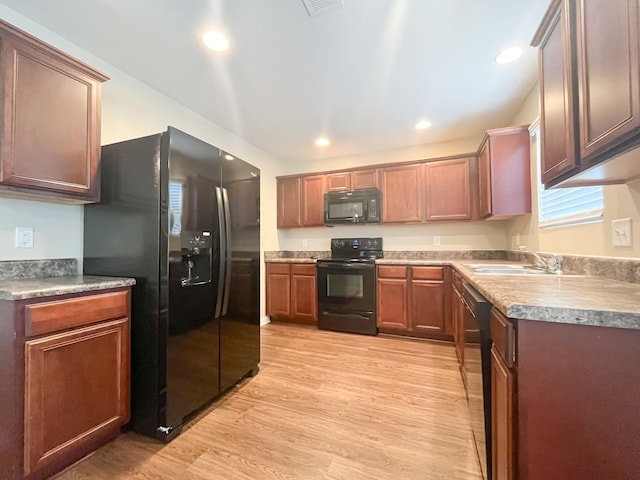 kitchen with a sink, light wood-style floors, black appliances, and recessed lighting