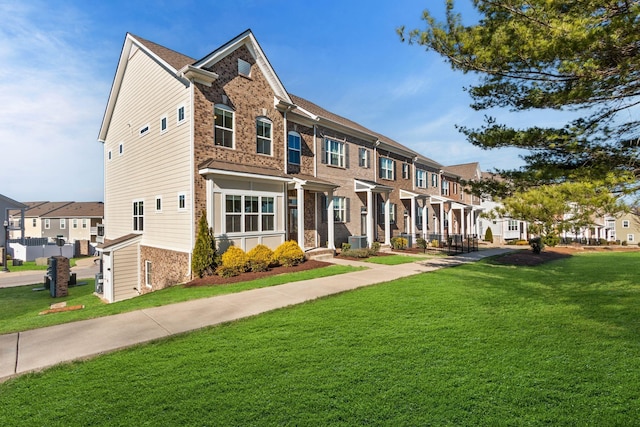 view of property featuring a residential view, brick siding, and a front lawn