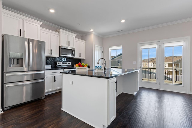 kitchen with a sink, appliances with stainless steel finishes, white cabinets, and an island with sink