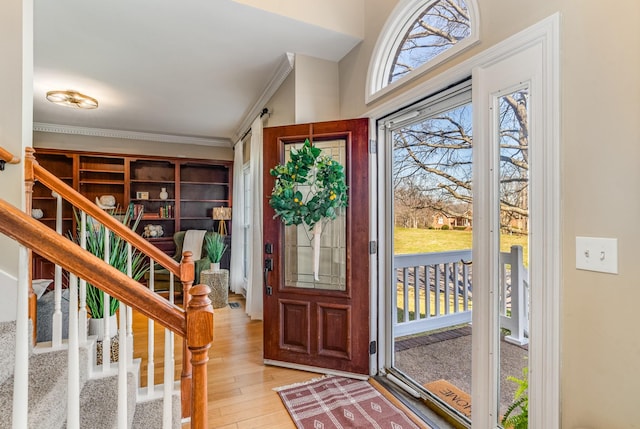 entryway featuring stairway, light wood-style floors, and ornamental molding