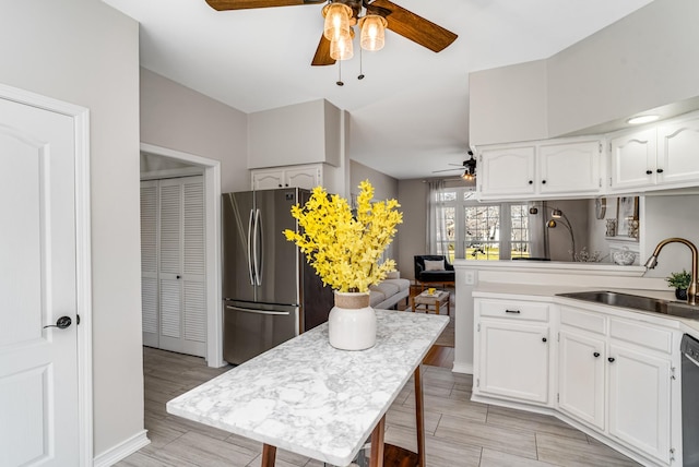 kitchen featuring a sink, white cabinetry, dishwasher, and freestanding refrigerator