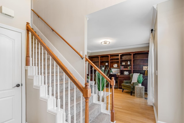 staircase featuring wood finished floors and ornamental molding