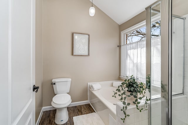 bathroom with a garden tub, toilet, wood finished floors, baseboards, and vaulted ceiling