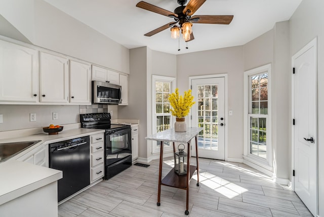 kitchen featuring a sink, black appliances, white cabinets, light countertops, and tasteful backsplash