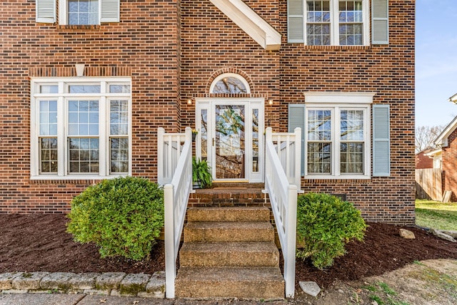 entrance to property with brick siding and fence