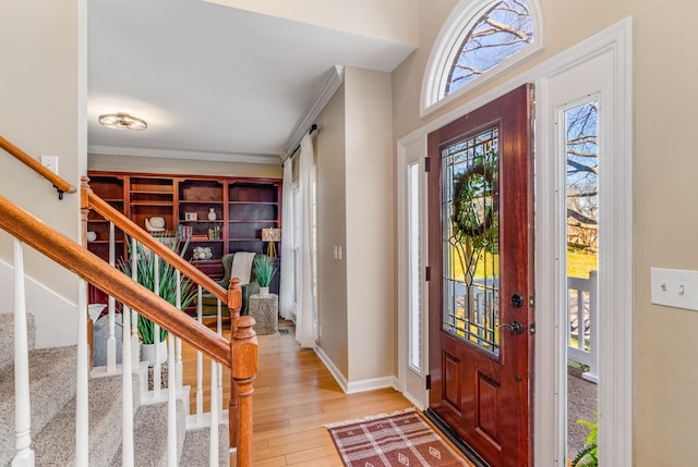 entrance foyer featuring stairway, baseboards, light wood-style floors, and crown molding