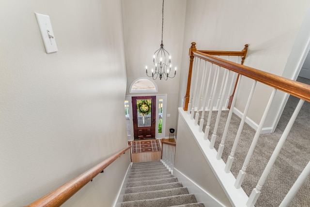 stairway with a high ceiling, an inviting chandelier, and carpet