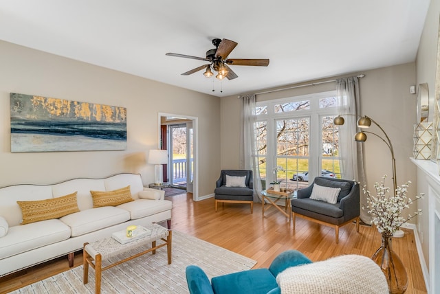 living room featuring baseboards, a ceiling fan, and wood finished floors