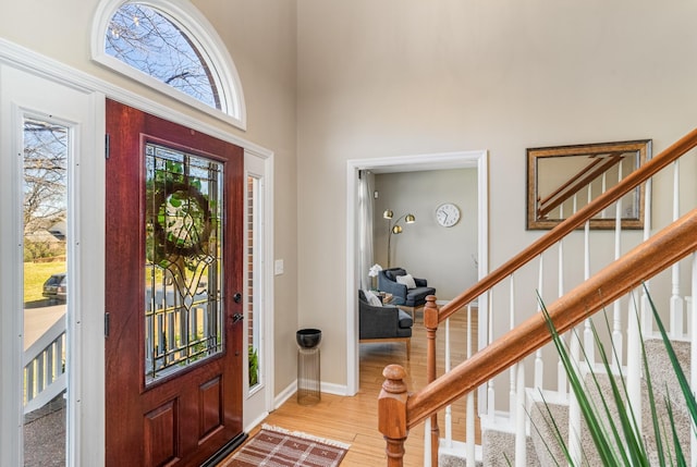 foyer featuring stairway, wood finished floors, baseboards, and a towering ceiling