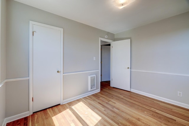 unfurnished bedroom featuring wood finished floors, visible vents, and baseboards