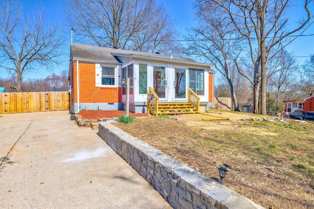 bungalow featuring fence, entry steps, concrete driveway, crawl space, and brick siding