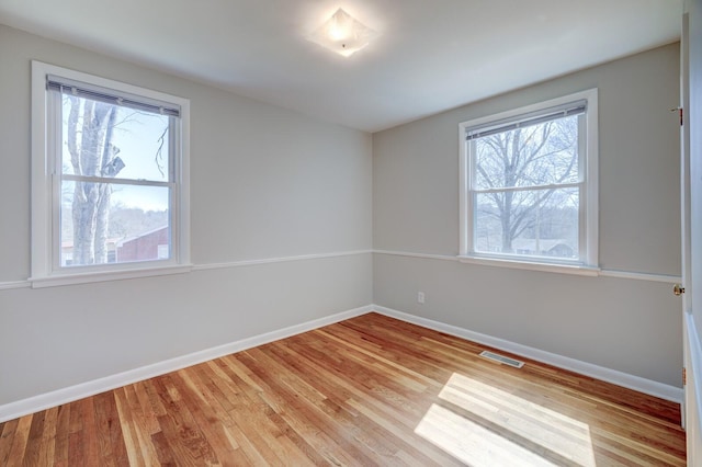 empty room featuring light wood-style flooring, baseboards, and visible vents