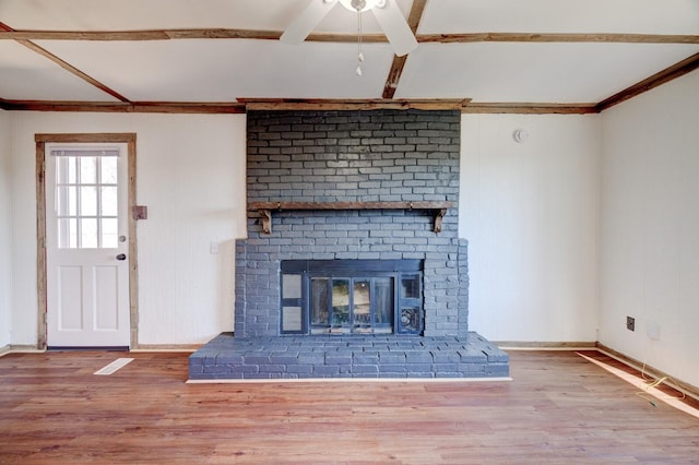 unfurnished living room featuring a brick fireplace, baseboards, and wood finished floors