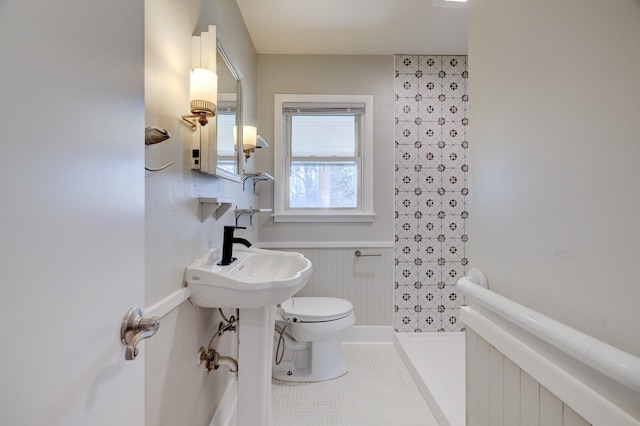 bathroom with tile patterned flooring, toilet, a wainscoted wall, and walk in shower