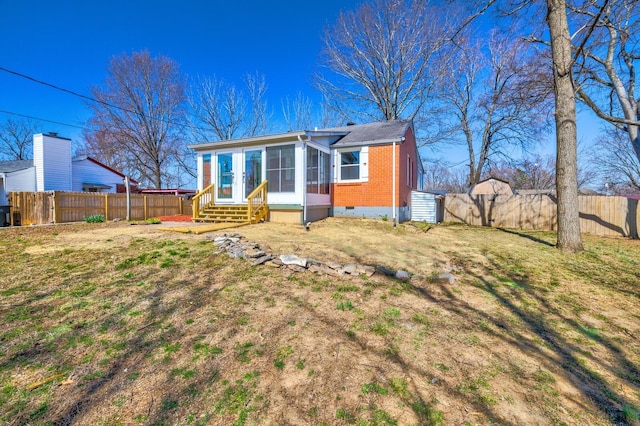 rear view of house with a fenced backyard, a sunroom, entry steps, crawl space, and brick siding