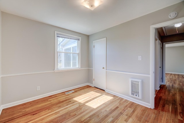 spare room with visible vents, attic access, baseboards, and wood finished floors